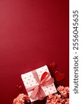 Valentines Day gift box with red hearts, pink flowers, and heart-shaped decorations on a red background. Perfect for romantic and festive celebrations