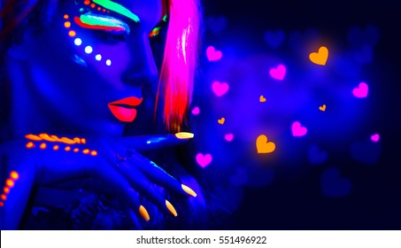 Valentine's Day girl on disco party. Fashion model woman in neon light, flying Valentine neon hearts. Beautiful model girl, painted fluorescent make-up, Body Art design of female in UV. Night club