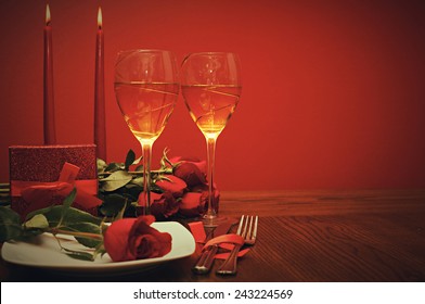 Valentines day: glasses of vine, red roses, candles and present a retro photo