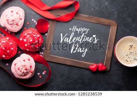 Valentine's day greeting card with delicious sweet cupcakes and coffee cup on stone background. Top view
