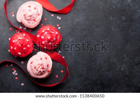 Valentine's day greeting card with delicious sweet cupcakes on stone background. Top view with space for your greetings