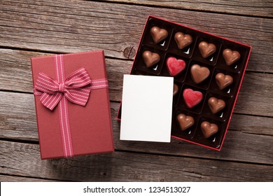 Valentines Day Greeting Card With Heart Chocolate In Box On Wooden Table. Top View With Space For Your Greetings