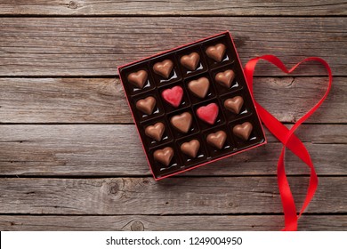 Valentines Day Greeting Card With Heart Chocolate In Box On Wooden Table. Top View With Space For Your Greetings