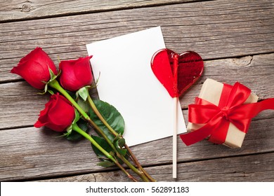 Valentines Day Greeting Card, Red Rose Flowers, Candy Heart And Gift Box On Wooden Table. Top View With Copy Space 