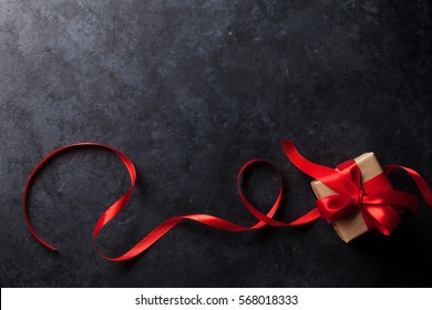 Valentines day greeting card. Red ribbon and gift box on stone table. Top view with copy space  - Powered by Shutterstock