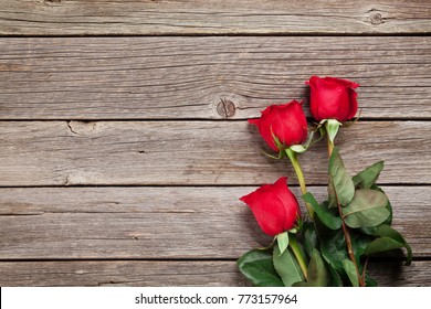 Valentines day greeting card. Red roses on wooden table. Top view with space for your greetings