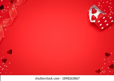Valentines day greeting card template. Gift boxes, heart decor and candy sweets over red background. Top view flat lay with copy space