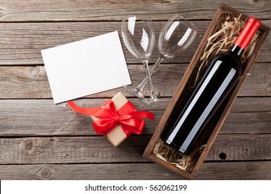 Valentines day greeting card. Wine and gift box on wooden table. Top view with copy space   - Powered by Shutterstock