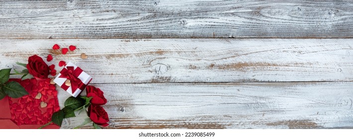 Valentines day greeting concept with envelope of small gold and red hearts, rose flowers plus a gift box on white rustic wood background - Powered by Shutterstock