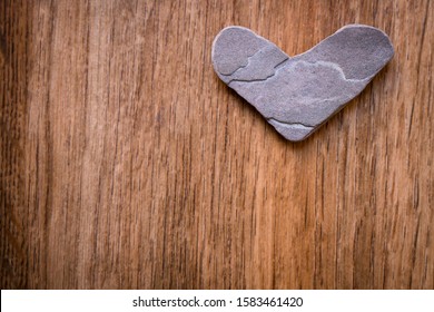 Valentine's Day, grey heart shaped stone on wooden background with copy space on left hand side - Powered by Shutterstock