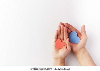 Valentine's Day, hearts blue and red made of paper are held in the hands of a couple in love. Top view. Copy space. Place for text.