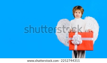 Valentines day. Little angel in wings with Valentine present. Cupid boy with gift box. February 14.