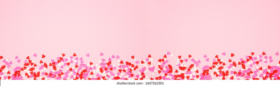 Valentines Day Long Border Banner With Candy Heart Sprinkles Over A Pink Textured Background. Copy Space.