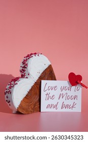Valentine's Day LOVE YOU TO THE MOON AND BACK wishes saying caption on greeting card Delightful heartshaped pastry croissant treat, beautifully topped with colorful frosting galore. Copy space. Food