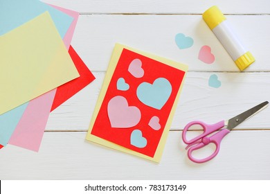 Valentines Day Or Mothers Day Card With Pink And Blue Hearts, Scissors, Glue Stick, Colored Paper Sheets On A Wooden Table. Easy Art And Craft With Paper For Kids. Top View