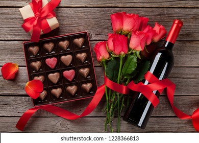 Valentines Day With Red Roses, Wine Bottle And Chocolate Box On Wooden Table. Top View