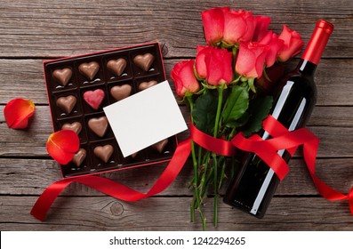 Valentines Day With Red Roses, Wine Bottle And Chocolate Box On Wooden Table. Top View With Space For Your Text