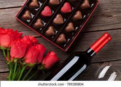 Valentines Day With Red Roses, Wine Bottle And Chocolate Box On Wooden Table. Top View