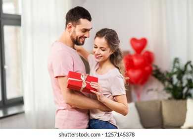 Valentines Day, Relationships And People Concept - Happy Couple With Gift Box Hugging At Home