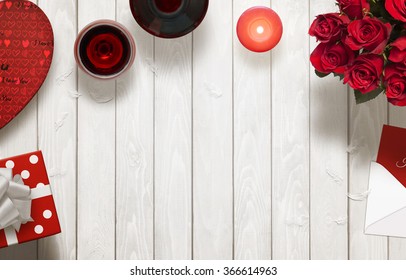 Valentines Day Romantic Background With Gifts, Glasses Of Wine, Candle, Roses, Envelope On Wooden Table.