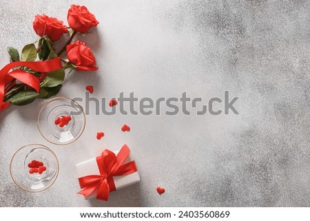 Valentine's day romantic concept with sparkling wine, gift , hearts and red roses on gray background. View from above. Copy space.