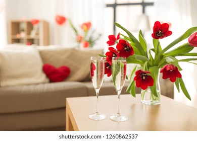 Valentines Day, Romantic Date And Holidays Concept - Two Champagne Glasses And Red Tulip Flowers On Table In Living Room Or Home