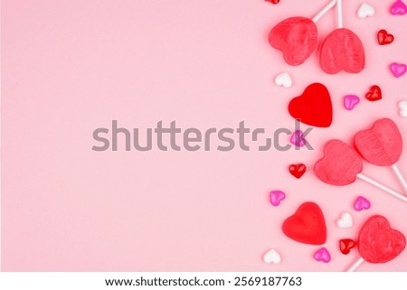 Valentines Day side border of candy hearts and lollipops. Overhead view on a pink background. Copy space.