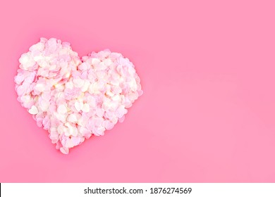 Valentine's Day, wedding, love concept. Big heart made of pastel confetti isolated on pink background. Top view, flat lay, copy space.