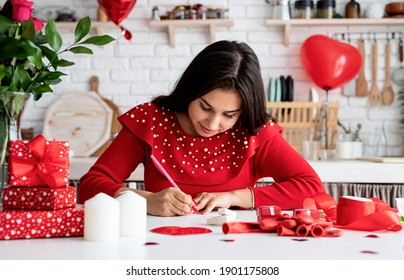 Valentines Day. Woman In Red Dress Writing Love Letter Sitting At The Decorated Kitchen