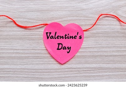 Valentine's Day words on red heart shaped stick note with red string isolated on gray wooden background. Valentine's day concept - Powered by Shutterstock