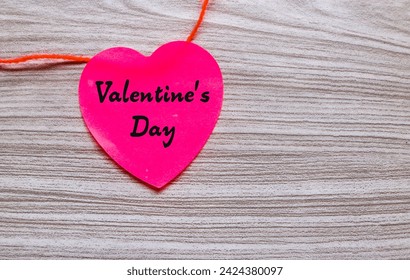 Valentine's Day words on red heart shaped stick note with red string isolated on gray wooden background. Valentine's day concept - Powered by Shutterstock