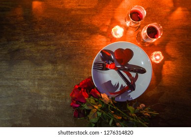 Valentines dinner romantic love concept / Romantic table setting decorated with fork spoon on plate and couple champagne glass wine roses with candlelight on table dinner night light top view