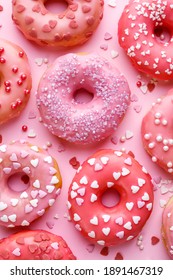 Valentine's donuts with icing and sugar sprinkles on a pink background top view