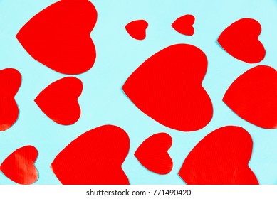 Valentines, red paper love heart cut outs of varying sizes on a pale blue background