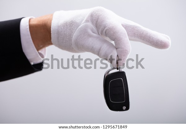 Valet\'s\
Hand Holding Car Key Against White Background\

