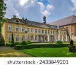 Valkenburg, South Limburg, Netherlands. May 14, 2023. Chateau St. Gerlach, backyard terrace with tables, chairs and closed umbrellas, green grass and bushes, view from a side angle