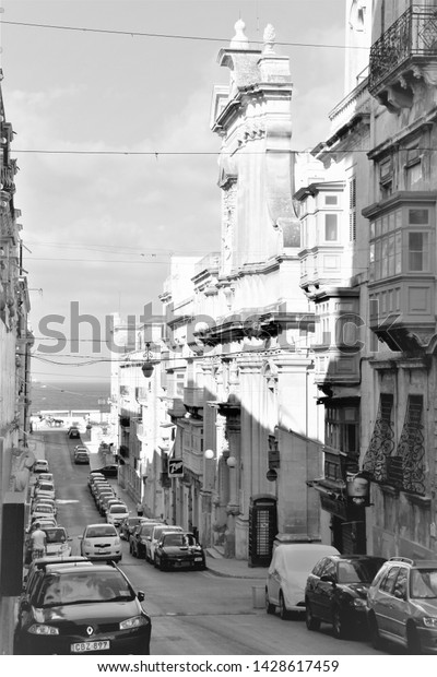 Valletta, Malta, August 2015. Black\
and white view of the old street and modern cars on\
it.