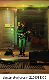 VALLETTA, MALTA - Dec 19, 2021: Busker Playing A Guitar In The Evening In The Alcove Of A Shop  Wearing A Mask Because Of Covid-19   Guitar Case Open For Donations