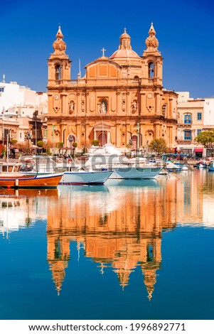 Valletta, Malta. Msida Marina boat and St Joseph Church reflection into water.