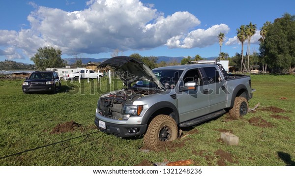 Valley Center, CA / USA - February 22, 2019: A Ford F150\
and a Toyota Sequoia are stuck in deep mud in a field, working on\
getting pulled out via self rescue with winch.                     \
        