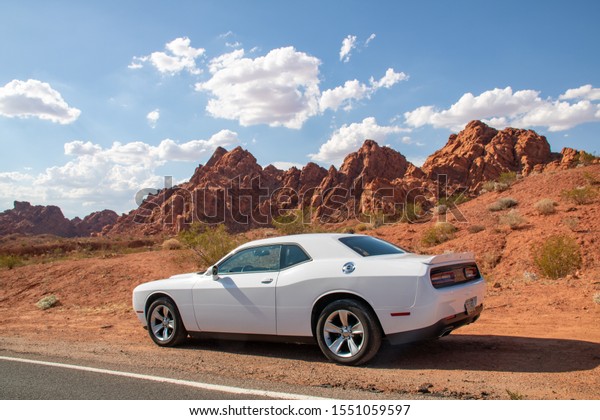 Valley of Fire,\
Nevada, USA - July 2019: White Dodge Challenger in front of red\
rocks in the Valley of\
Fire.