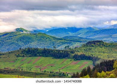 In the valley on the mountainside stretched rectangular agricultural land plots against the backdrop of the picturesque landscape of the Carpathian Mountains, shrouded in mist. - Shutterstock ID 1454740088