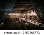 Valmiera, Latvia - August 10, 2023 - Elegant banquet hall with long dining tables, decorated with flowers and fairy lights, ready for a festive event.