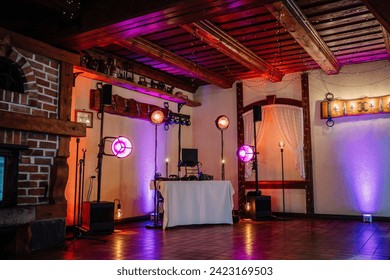Valmiera, Latvia - July 7, 2023 - Rustic wedding venue interior with purple lighting, DJ booth, and exposed wooden beams.