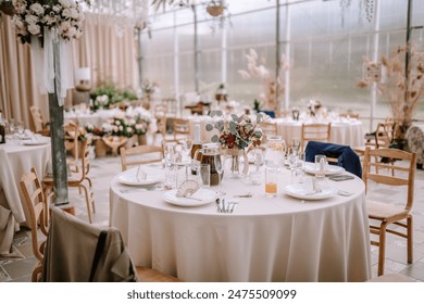 Valmiera, Latvia - September 9, 2023 - Elegant wedding reception setup with round tables, floral centerpieces, and champagne glasses in a beautifully decorated venue. - Powered by Shutterstock