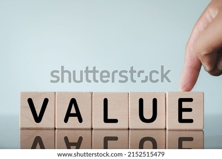 Value for business concept.,Selective focus on VALUE word on wooden cube with hand touching over white background.