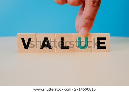 Value creation concept. Hand selecting a wooden cube with letter U, symbolizing importance, added value, business growth, customer focus, decision making, and strategic priorities.