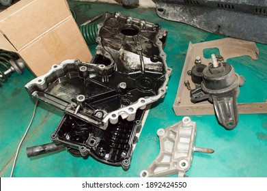 The Valve Cover And Front Covers Of The Internal Combustion Engine Lie On The Green Floor In The Auto Repair Shop