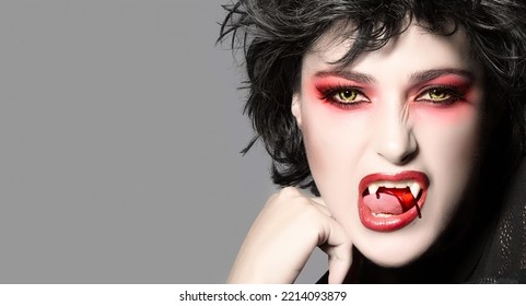 Vampire. Beautiful Young Woman With Fancy Makeup, Bloody Fangs And Wolf Lenses. Halloween Concept. Black And White Portrait With Copy Space