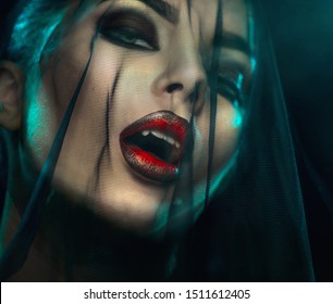 Vampire Halloween Woman portrait with black veil on a face. Beauty Sexy Vampire Girl with teeth, bloody red lips. Vampire makeup Fashion Art design. Mysterious model girl make up. Fangs. Darkness